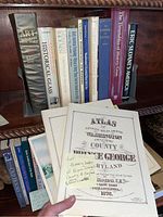 Full view of bookshelf with a variety of history books, atlases and manuals related to antiques, art, architecture, Maryland local history, glass, and woodworking.