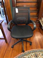 Front view of black mesh office chair showing seat, backrest, and armrests.