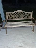Front view of outdoor bench showing full cast iron frame with wood slat seating and lattice-design backrest.