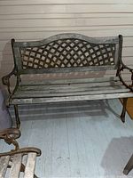 Front view of cast iron bench showing wood slat seat and lattice pattern backrest.