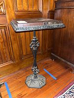 Full view of the marble top cast iron plant stand showing the ornate cast iron base and square marble top.