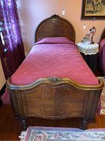 Full view of bed frame with bedding showing the wooden sleigh bed shape and pink bedspread.
