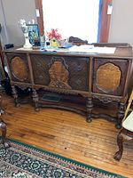 Full view of the wooden buffet showing front carved panels, drawer pulls, and turned legs.
