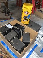 Photo of box with multiple vintage black box cameras and Wolverine converter box inside a cardboard box.