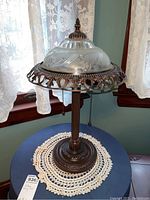 Full view of the vintage table lamp showing metal base, decorative metal frame around glass shade insert, and pull chains.