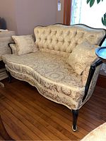 Full front and side view of couch with two pillows on wooden floor.