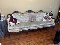 Full front view of the sofa showing carved wood frame, tufted back and seat cushions