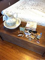 Wide view of wash basin set and hair accessories on wooden chest showing overall lot contents