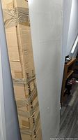 Two white primed barn doors leaning against the wall next to a boxed hardware kit wrapped with tape.