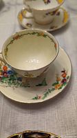 Photo showing china tea cup and matching saucer with floral patterns and gold rim, placed on a white cloth.