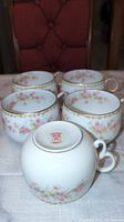 Six floral porcelain tea cups with pink rose designs and gold trim, marked Elite Works Limoges France on bottom.