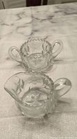 Photo of two crystal dishes including a small handled crystal dish and a larger handled dish with scalloped top edge.