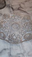 Clear crystal plate with intricate cut glass patterns including starbursts and diamond shapes, placed on a marble surface.