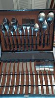 Photo of open cutlery case showing knives, forks, spoons organized in two layers