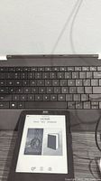 Photo of Kobo e-reader device and Microsoft Surface keyboard together showing keyboard layout and active e-reader screen.