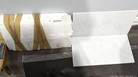 White marble tiles stacked with styrofoam and cardboard support, showing sparkle finish and size ratio