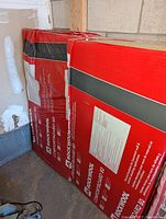 Two unopened red packages of Rockwool Comfortboard 80 insulation boards stacked side by side against a wall.