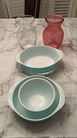 View of all items together showing two glass vases and three teal dishes, with one dish showing winter snowflake pattern.