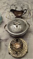 Overview of gravy boat, several hot plates and dish stands arranged on table.