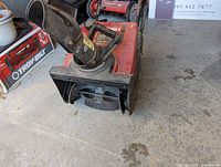 Front angled view of red Toro snow thrower showing auger, chute, and part of handle.