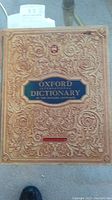 Front cover of an antique Oxford Dictionary with ornate embossed gold and blue design