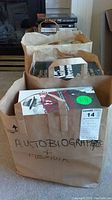 Four brown paper bags filled with books, front bag labeled 'Autobiographies & Memoir' handwritten on the side