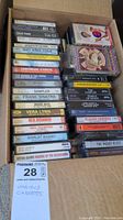View of two columns of various music cassette tapes in a cardboard box showing titles and artists.