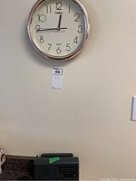 Wall clock mounted on wall above general electric black radio on countertop.
