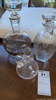 Set of three glass decanters on wooden table showing size and shape variety