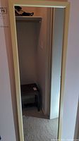 Photo showing full view of the rectangular wall mirror mounted or standing against a beige wall with a beige plastic frame.