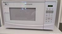 Front view of the white Frigidaire microwave oven showing door and display panel.
