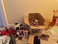 Wide view showing assorted Christmas decorations including plush bears, snowmen, poinsettias, and decoration bags alongside the wooden reindeer stand.