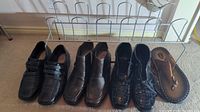 Four pairs of men's shoes resting on carpet with metal shoe rack behind