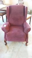 Front view of wingback reclining chair showing padded armrests, high back, and reddish fabric upholstery.