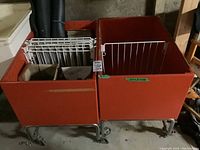 Two orange vintage rolling carts side by side with metal wire dividers and contents inside, on caster wheels.