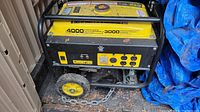Full side view of yellow and black generator on wheeled base showing frame, wheels and folding handle.