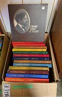 Photo showing the box sets arranged in a box, featuring the title 'Great Men of Music' with a sepia portrait on the largest box (Debussy). The visible spines are red, yellow, blue, and brown with embossed gold text listing composers.