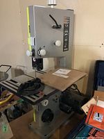 Front view of grey and green Ryobi benchtop bandsaw with metal table and fence