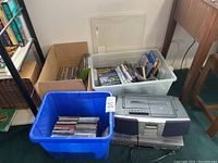 Wide view of bins containing CDs, DVDs, and Xbox games, plus Sony boombox and DVD/VHS player.