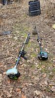 Two gas powered trimmers on the ground including Weeds Be Gone HG330 Aquatic Weed Cutter with chain blade and Yard Works trimmer with white fuel tank