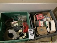 Five milk crates with assorted hardware items including screws, tape, wheels, and boxes of parts, both used and unused.