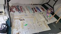 Wide view showing many necklaces laid out on a table with varied colors including whites, blues, reds, and multi-color beads