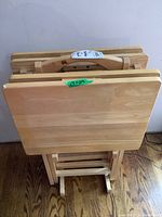 Top view showing the four wooden TV tables stacked closely with foldable legs.