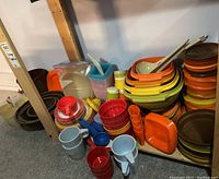 Shelf holding a variety of vintage Tupperware items including bowls, plates, cups, and trays in multiple colors
