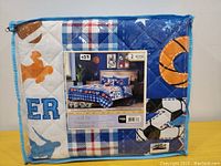 Front of packaging showing folded quilt and included pillow sham with 'All Star' sports theme design