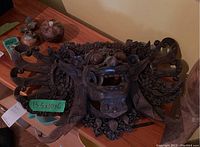 Front view of the hand-carved wood wall sconce showing the detailed grotesque face and ornamental curves, with size label visible.