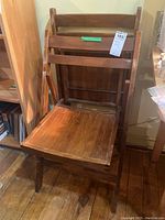 Two wooden folding chairs, front view showing slatted seat and backrest with noticeable scratches on the wood.