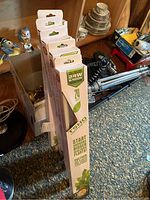 Photo showing five boxed SunBlaster T5HO lighting kits standing upright near a room corner with assorted household items in background.