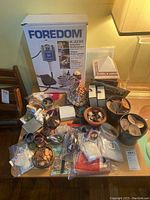 Wide view of lot on wooden table showing Foredom box, tools, moulds, coins and sewing items