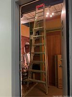 View of the ladder fully extended and resting against ceiling with red top section visible